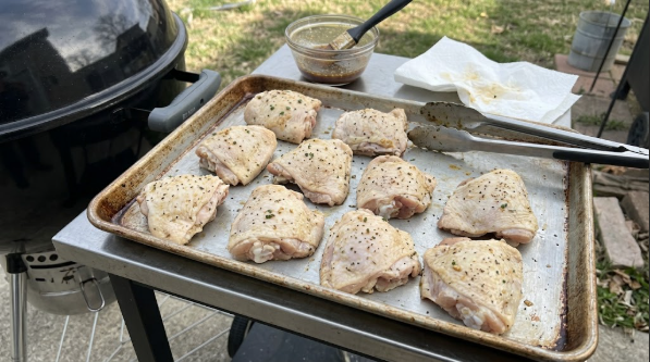 Patted-dry thighs on a sheet pan next to the grill, ready to cook