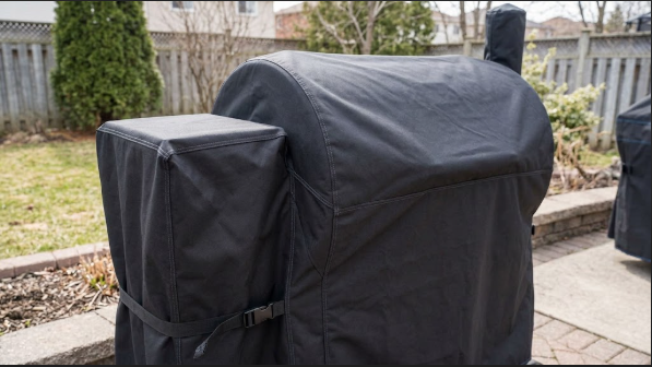 Pellet grill with the cover on and the hopper lid sitting snug beneath it