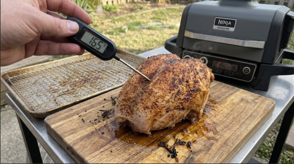 Finished turkey breast on the cutting board, skin deep golden brown, thermometer in the thickest part