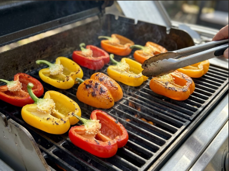 Bell pepper halves skin-side down on hot grates, showing the first char marks