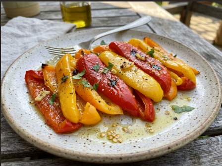 Whole blistered peppers steaming in a covered bowl, then peeled strips on a plate