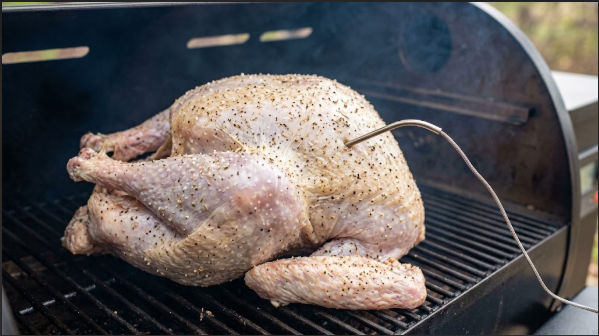 Dry-brined turkey on a pellet grill grate with a probe in the thickest part of the breast