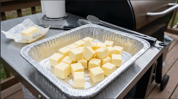 Four sticks of unsalted butter cut into cubes in a foil pan, before going on the smoker