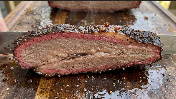A finished brisket slice showing a visible smoke ring and dark bark