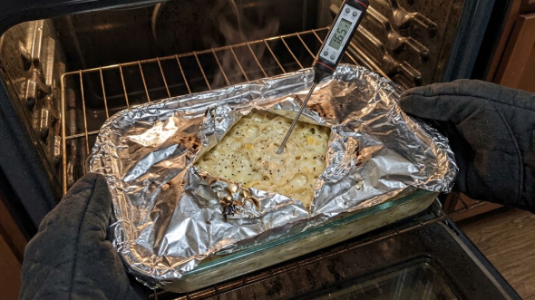 Instant-read thermometer inserted into the center of reheated Alfredo, showing 165°F