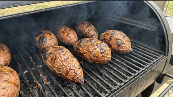 Smoked sweet potatoes on the grate, skins wrinkled and dark