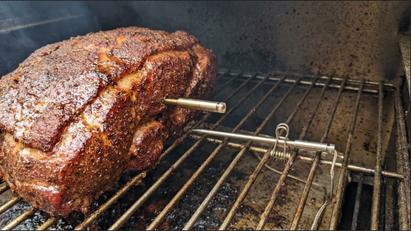 Wireless probe inserted into a pork butt, with the ambient probe clipped to the rack beside it