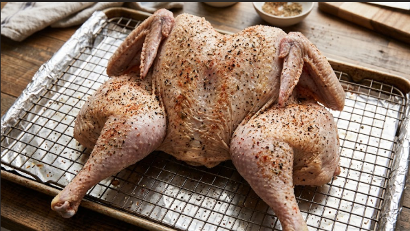 Seasoned flat turkey on a wire rack, skin dry after brining
