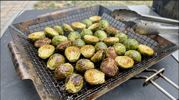 Finished grilled Brussels sprouts in the basket with dark brown cut sides and crispy leaves