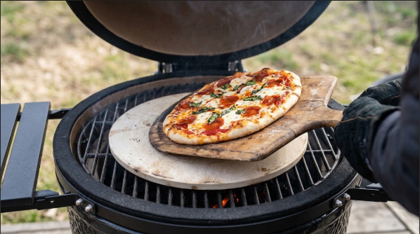 Preheated pizza stone on the cast iron grate with a loaded pizza on a peel