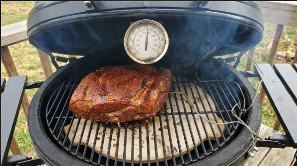 Pork butt on the grate with a probe in place and the lid thermometer reading about 250°F