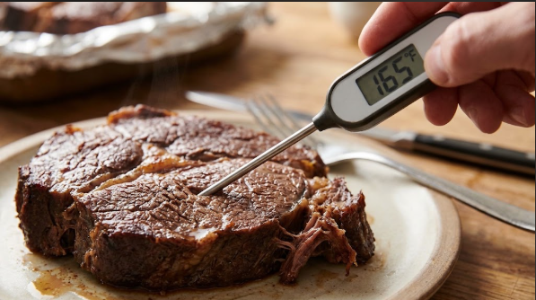 An instant-read thermometer reading 165°F in a thick piece of reheated chuck roast