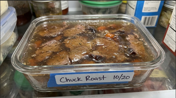 Leftover chuck roast in an airtight container with gelled juices on top, labeled with the date