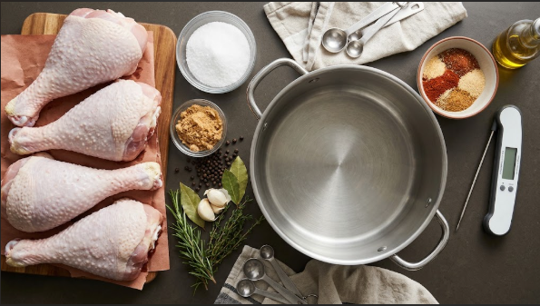 Raw turkey legs, brine ingredients, rub, and thermometer laid out on a counter