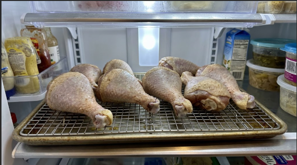 Brined legs air-drying on a wire rack in the fridge, skin tight and matte