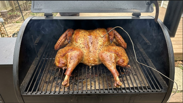 Turkey on the pellet grill at the 90-minute mark, golden-brown skin with a thermometer probe in the breast
