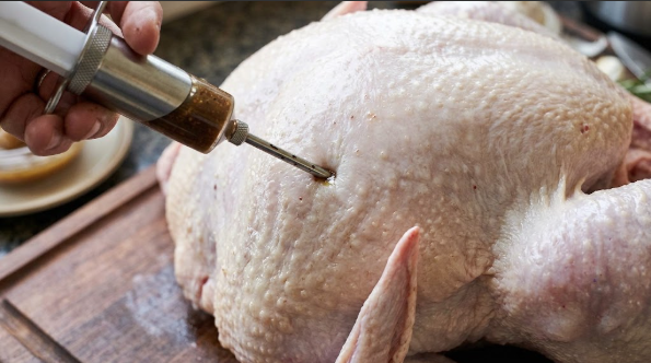  Close-up of injector needle going into the turkey breast at a shallow angle