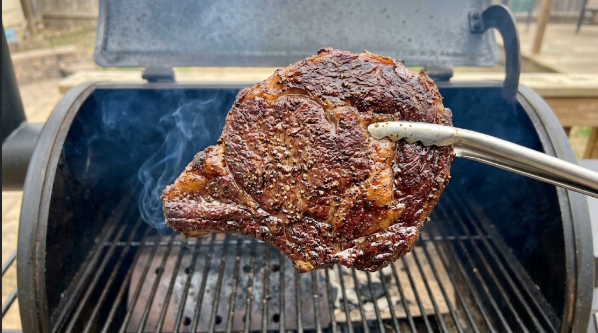 Ribeye coming off the smoker with a deep brown crust, before the hot sear