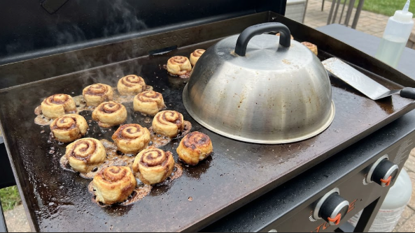 Cinnamon roll bites browning on the Blackstone with a metal dome