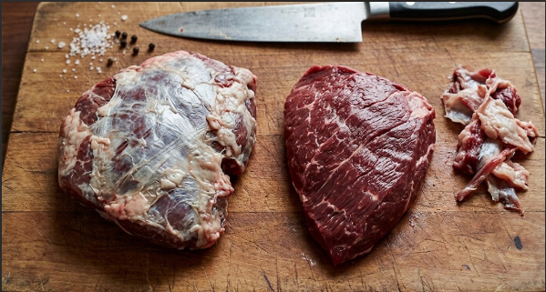 Untrimmed beef cheek next to a trimmed one, showing silver skin removed
