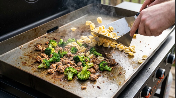 Sausage and broccoli sizzling on a Blackstone with orecchiette being tossed in