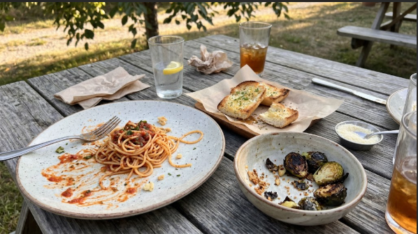  Finished plate of pasta, garlic bread, and charred Brussels sprouts on a picnic table