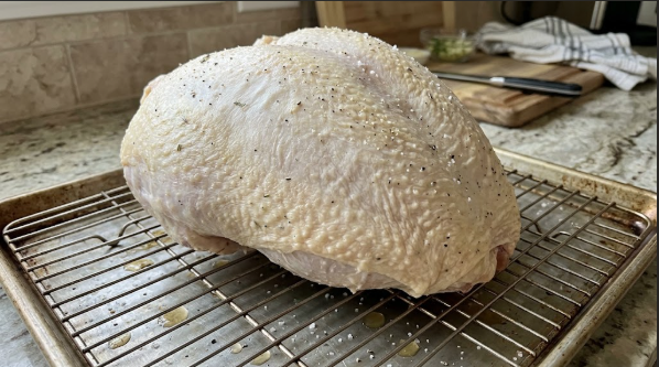 Turkey breast on a wire rack after the dry brine, skin looking dry and tight