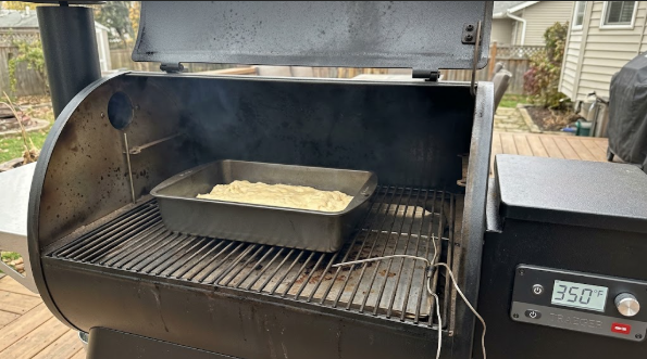 Cookie sheet on a pellet grill grate with a thermometer showing 350°F