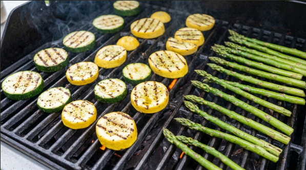 Sliced zucchini, squash, and asparagus with dark grill marks on a hot grate