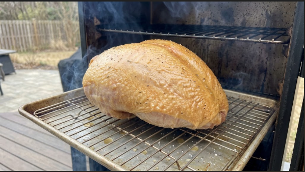 Turkey breast in the electric smoker at the 2-hour mark, skin golden with thin blue smoke