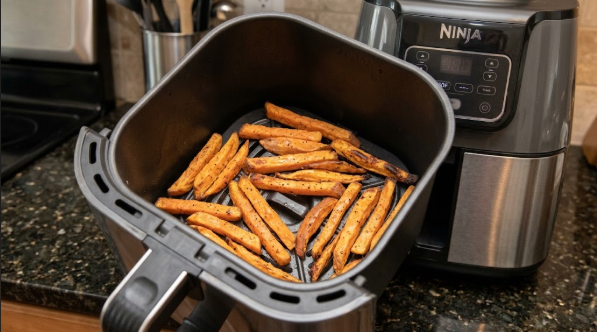 Sweet potato sticks spread in a single layer, half-way through cooking with browned edges