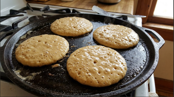 Pancakes on the griddle with bubbles forming on top, edges just starting to look dry