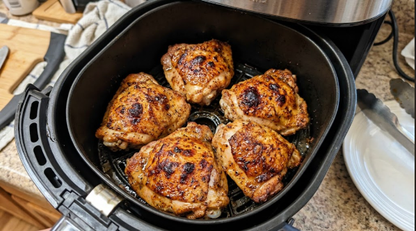  Finished air fryer chicken thighs in the basket, skin deeply golden and blistered