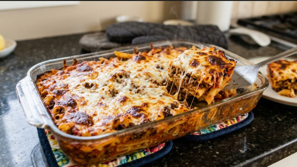 A finished 9x13 casserole fresh from the oven, cheese golden and bubbling, with one square lifted out