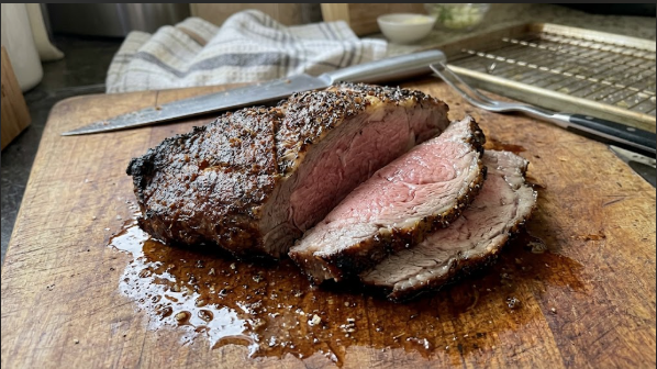 Prime rib on a cutting board with a thick, dark crust and a pink center