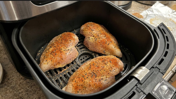 Seasoned breasts in a single layer in the air fryer basket before cooking, with space between each piece