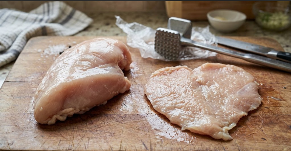 Chicken breast before and after pounding, side by side on a cutting board