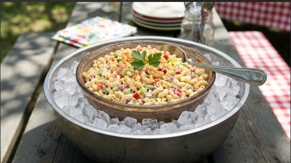  Macaroni salad in a serving bowl set inside a larger bowl of ice on a picnic table in shade
