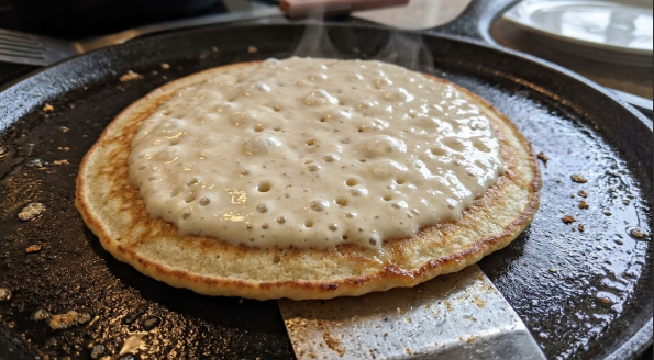 Batter bubbles forming on top of a pancake on the griddle just before the flip