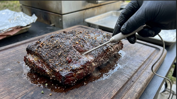 Probe thermometer sliding into the thickest part of a finished corned beef flat