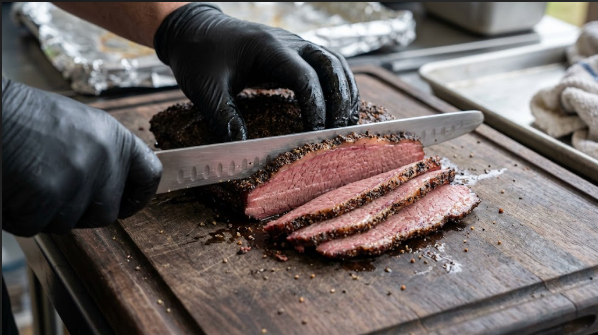 Corned beef being sliced against the grain into thin, even slices