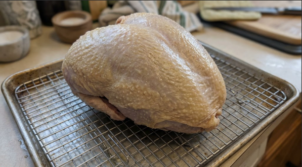 Dry-brined turkey breast on a wire rack, skin dry and tight, before the rub goes on