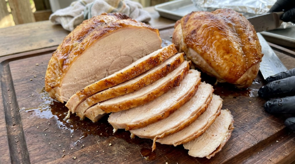 Cooked breast halves on a cutting board, slices fanned out showing a juicy interior