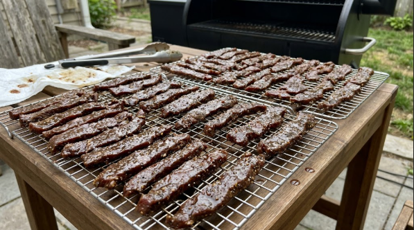 Marinated beef strips laid in a single layer on wire racks with small gaps between pieces, ready for the pellet grill