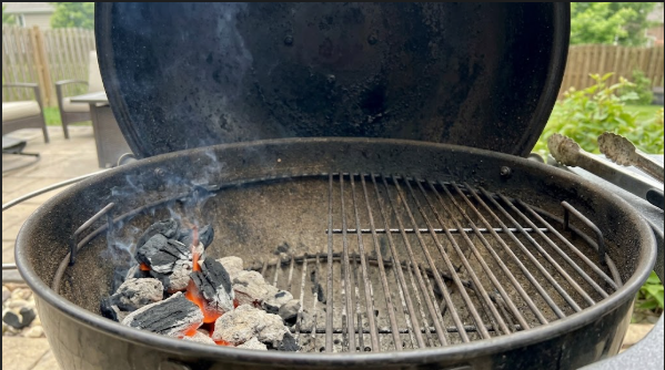 Charcoal banked on one side of a kettle grill with the empty cool side ready for chicken