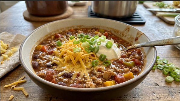 Bowl of finished smoked turkey chili topped with cheddar, sour cream, and green onions