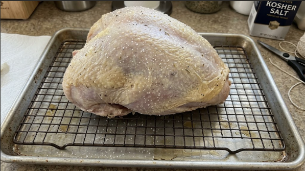 Dry-brined turkey breast on a wire rack set in a sheet pan, skin looking dry and tight